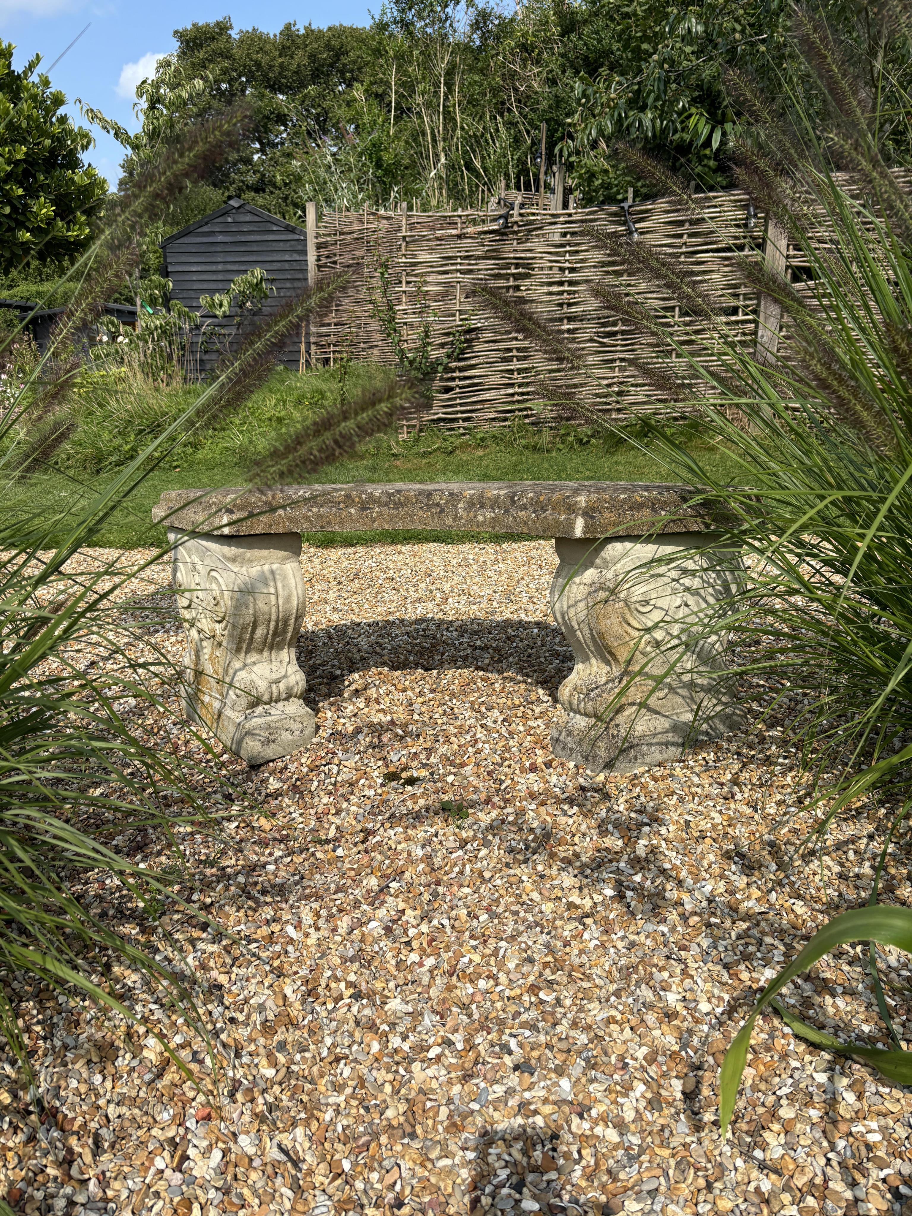 Two reconstituted stone benches, one curved, width 110cm, height 40cm, the other straight, width 114cm, height 44cm. Condition - both weathered, otherwise good condition